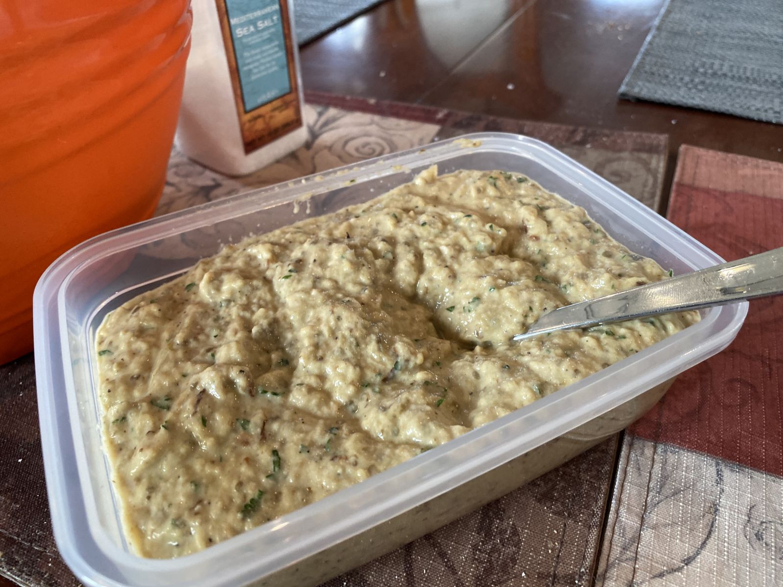Bowl of baba ganoush drizzled with olive oil and sprinkled with parsley and smoked paprika, surrounded by pita and vegetables.