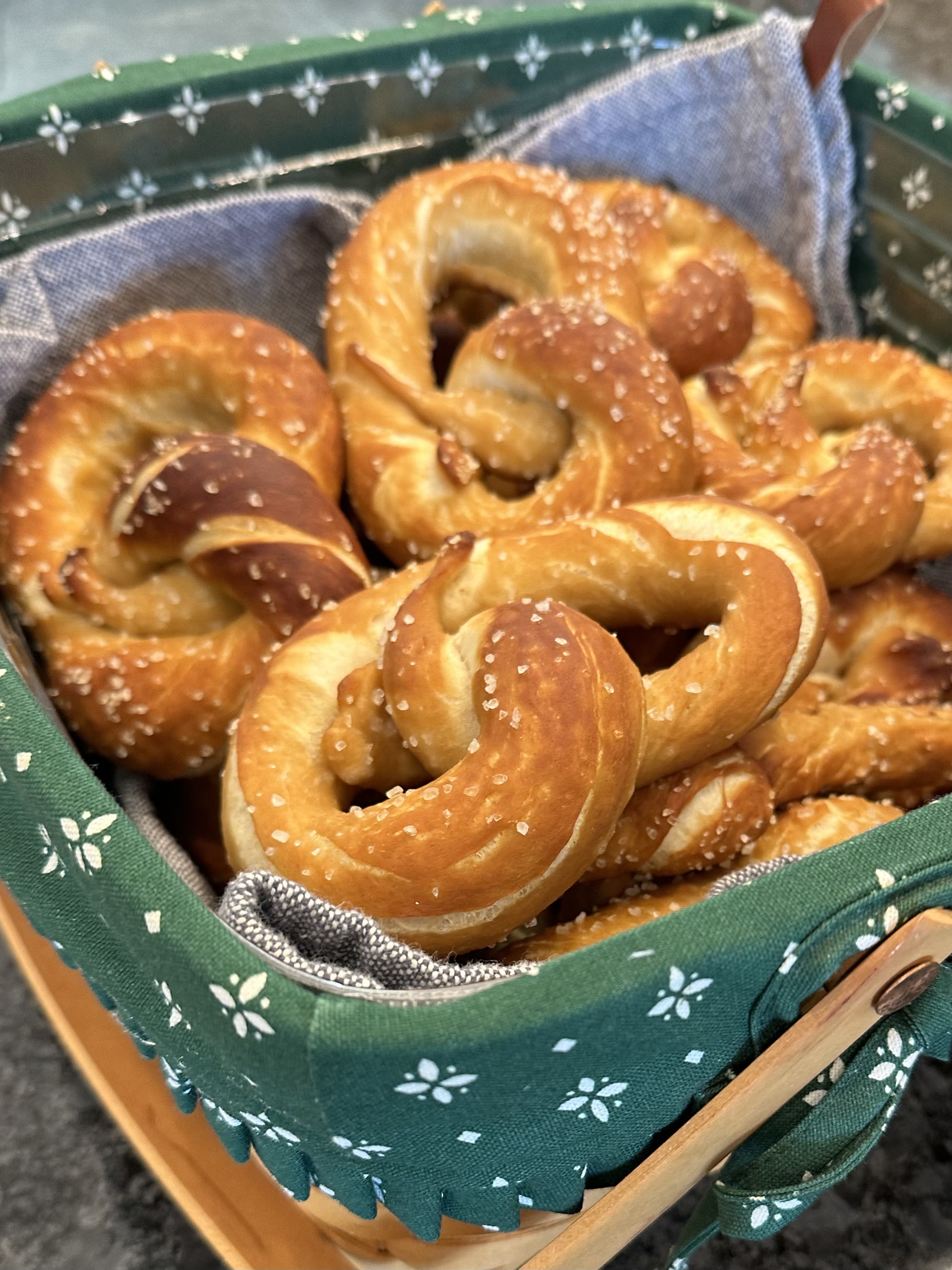 Golden brown soft pretzels on a tray with a bowl of Bavarian beer cheese spread garnished with chives and onions.
