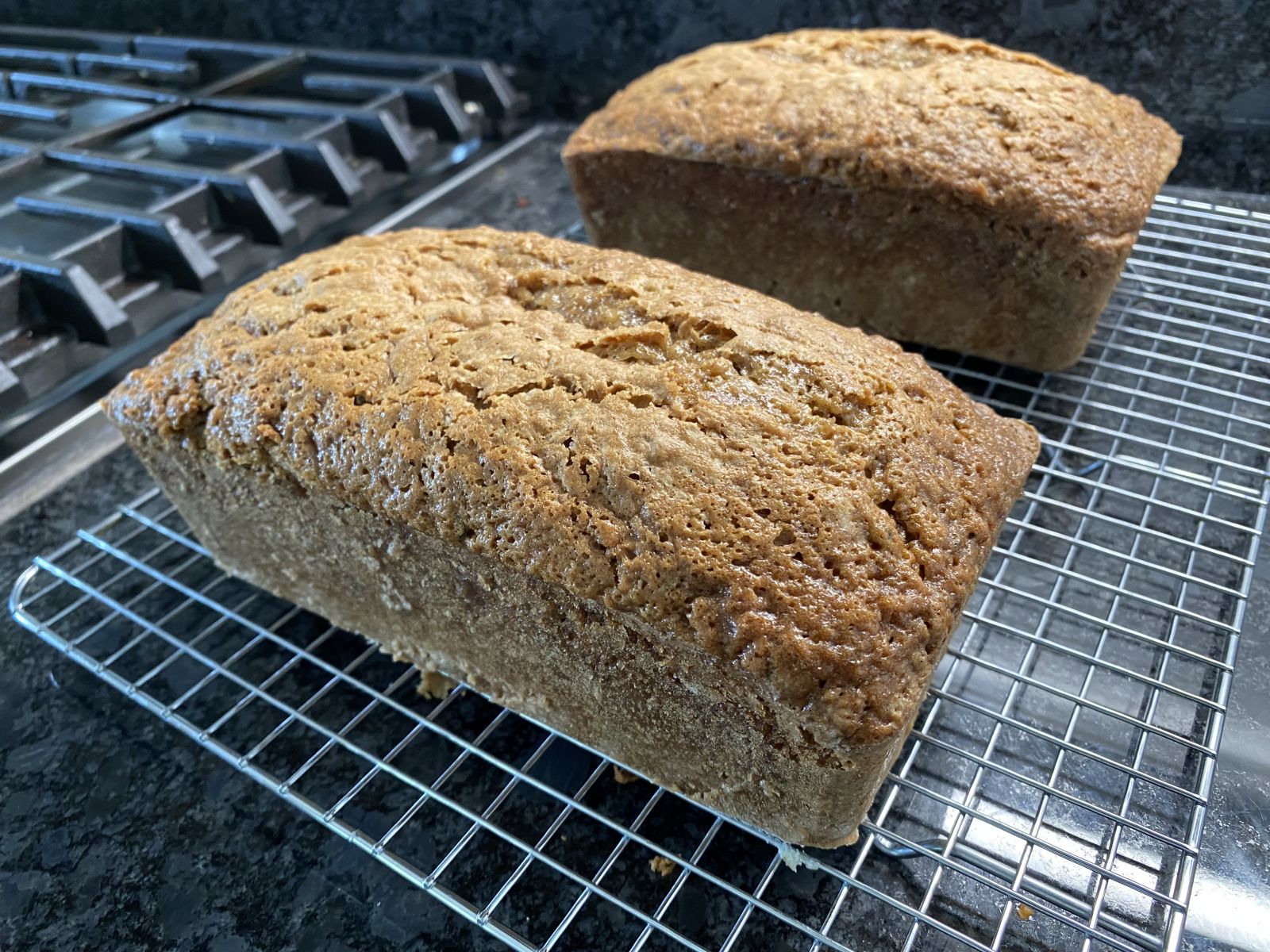 Two loaves of zucchini bread with pecans, one sliced to show the moist interior.