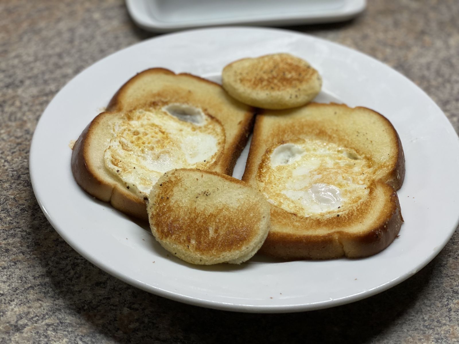 A slice of toast with an egg cooked in the center, served with the toasted bread circle.